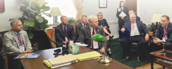 A diverse group of individuals sitting around a table in a room, engaged in a meeting or discussion.